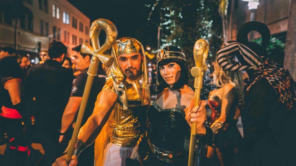 A couple wearing ancient Egyptian costumes while celebrating Halloween on a busy street