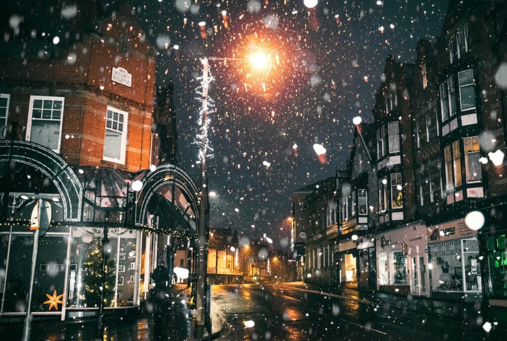 A snowy European street at night