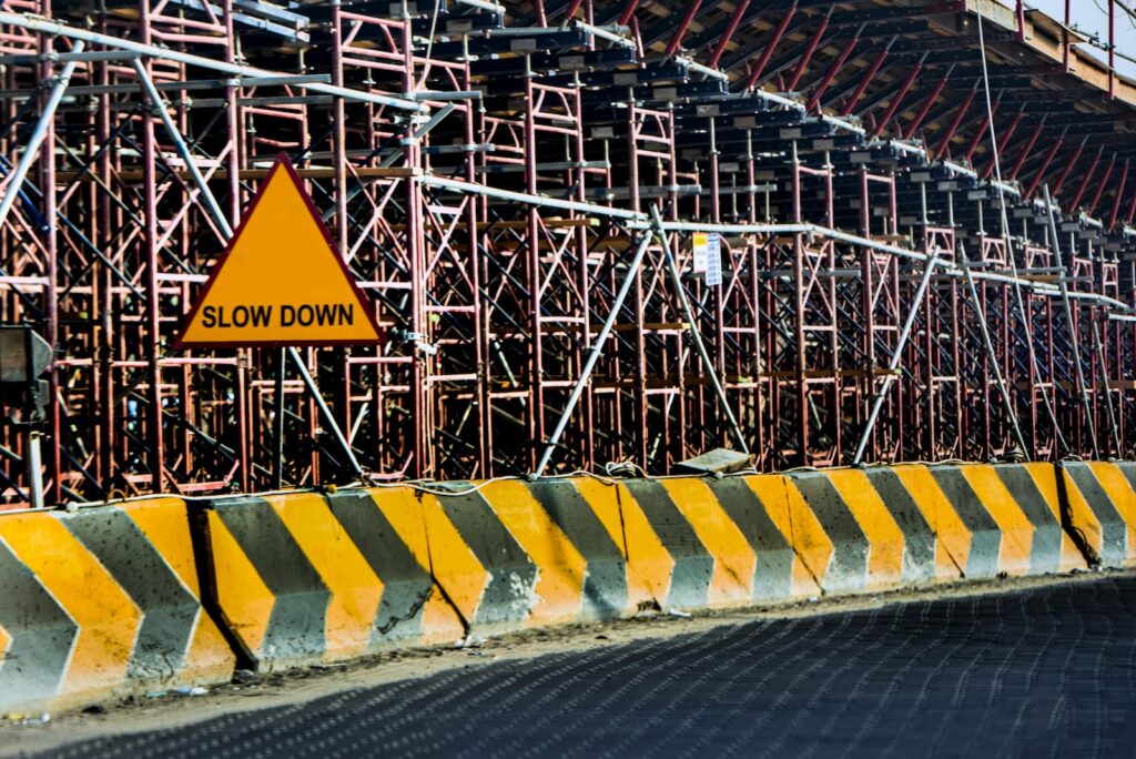 A 'Slow Down' sign along a road with heavy construction