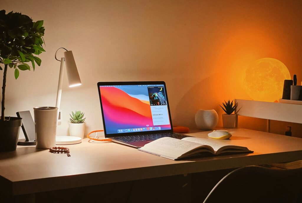 A clean work desk with laptop, notebook and lamp