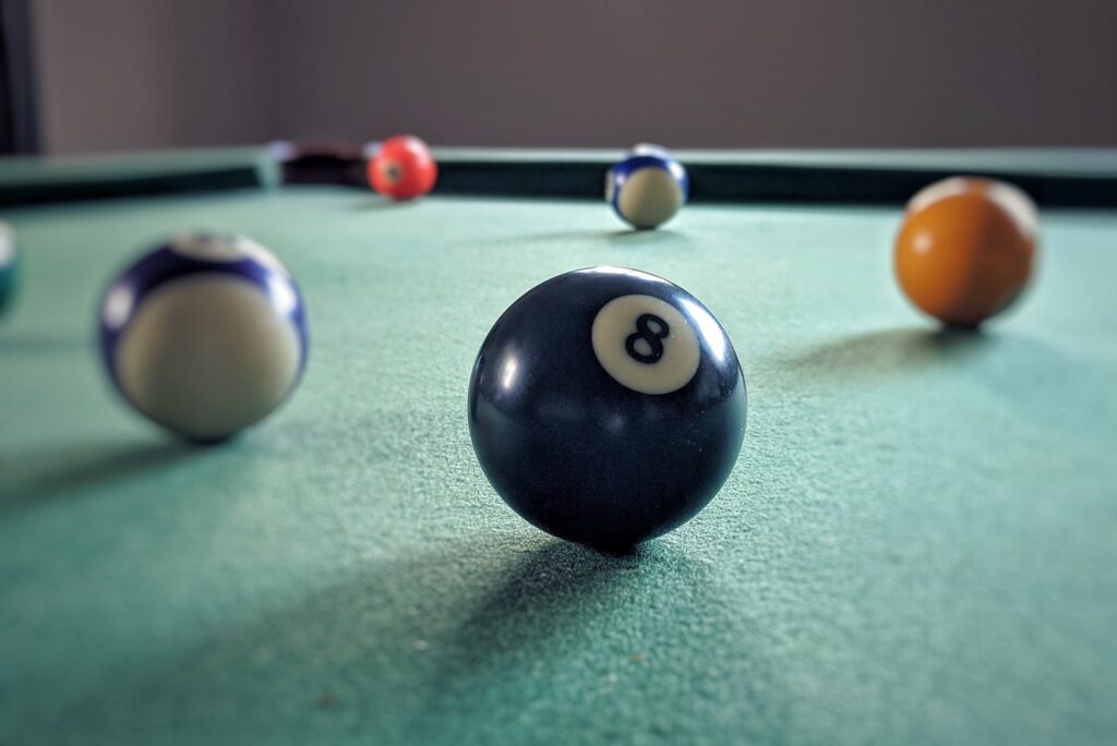 Pool balls on a pool table, with the eight ball in the foreground