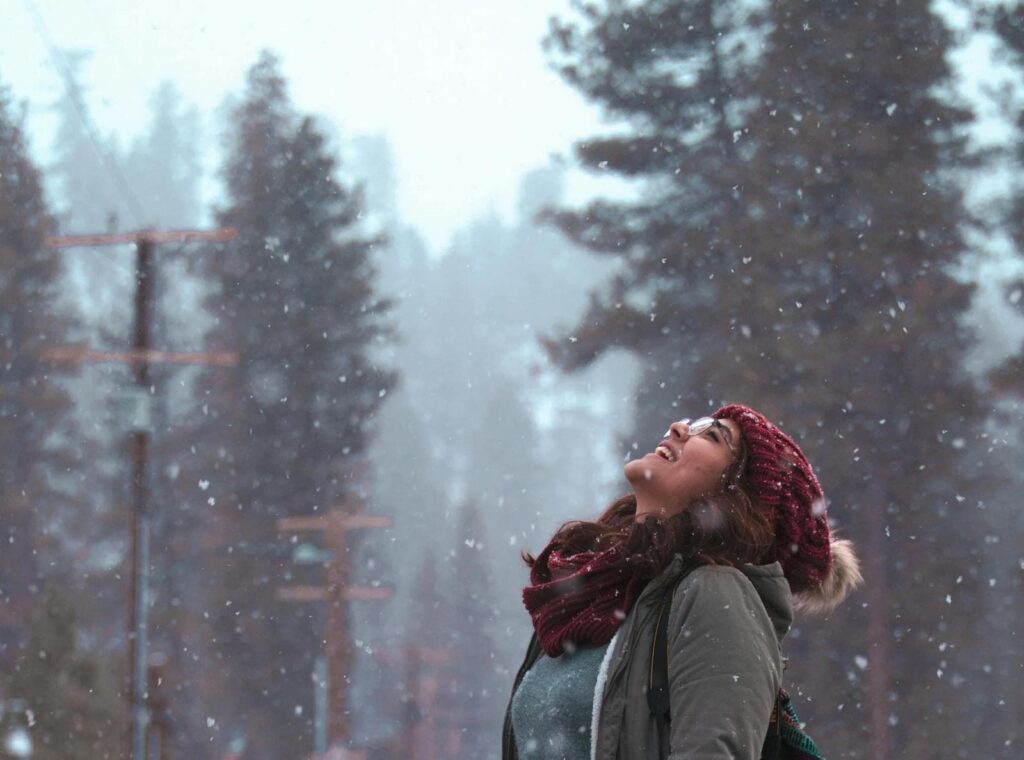 A woman looking toward the sky as snow falls
