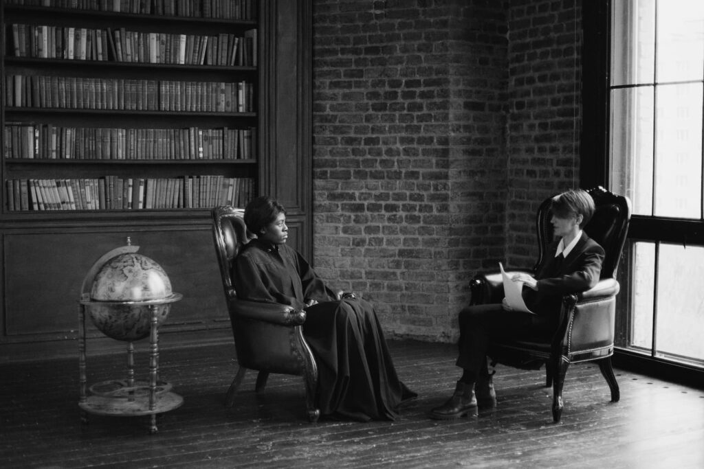 Two judges sitting beside a large globe in a library