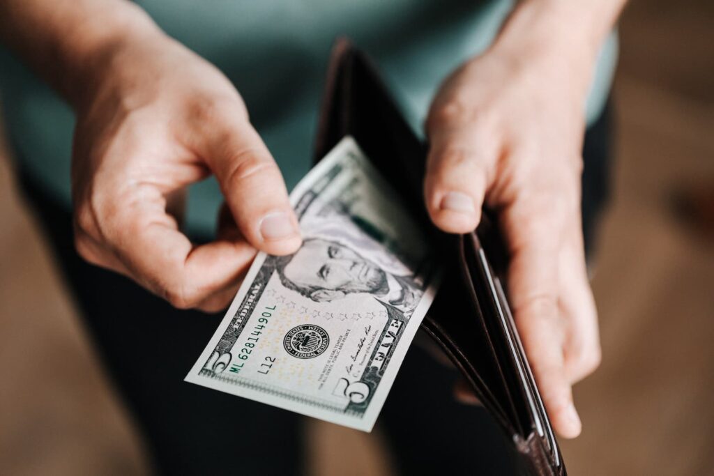A man pulling a five-dollar bill out of his wallet