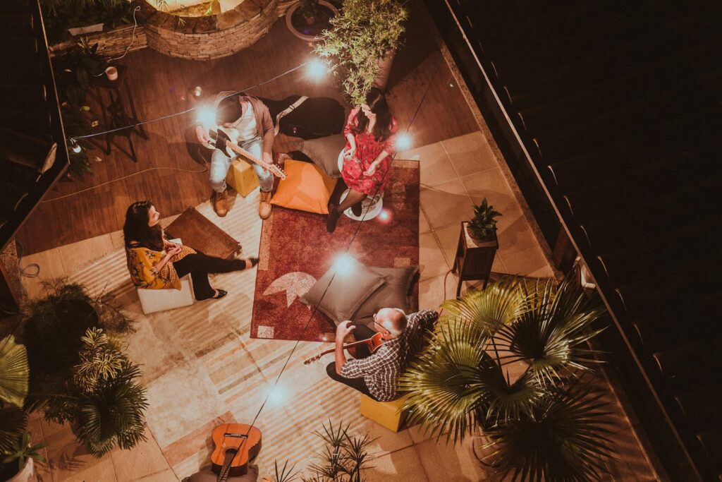 A small group of people with musical instruments gathered on a terrace at night