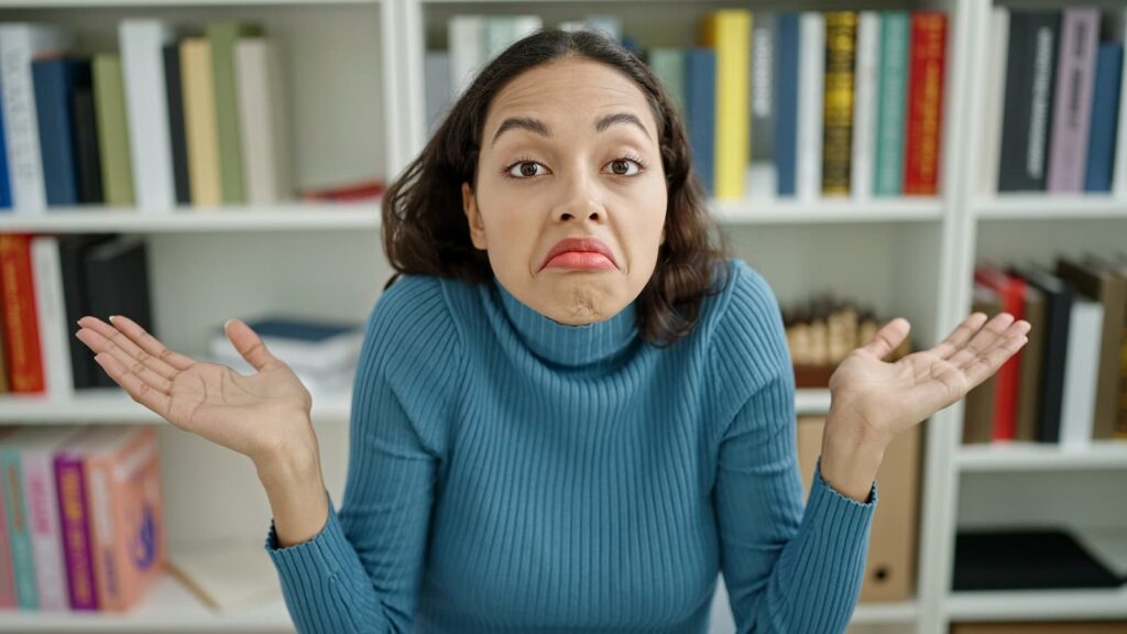A confused young woman shrugging her shoulders