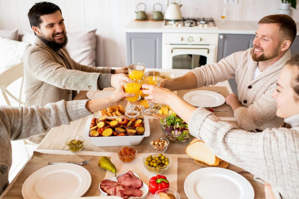 Smiling people toasting glasses while seated at a dinner table