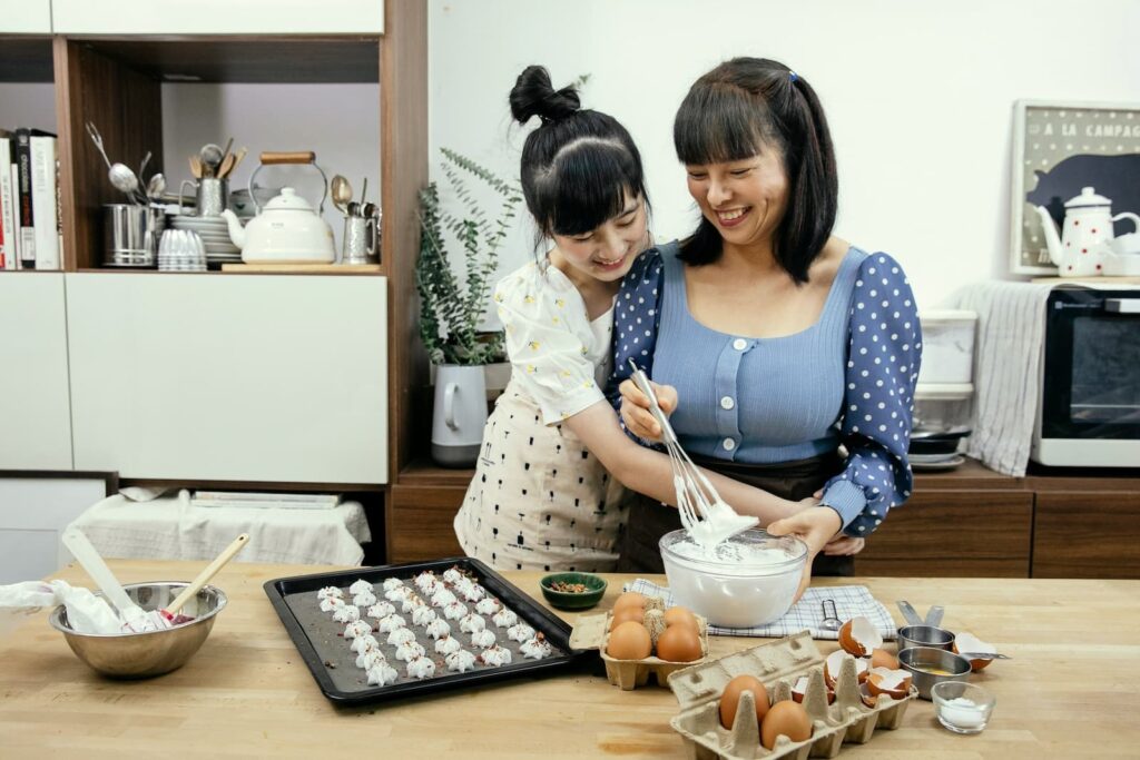 A mother and daughter smiling while baking in a kitchen