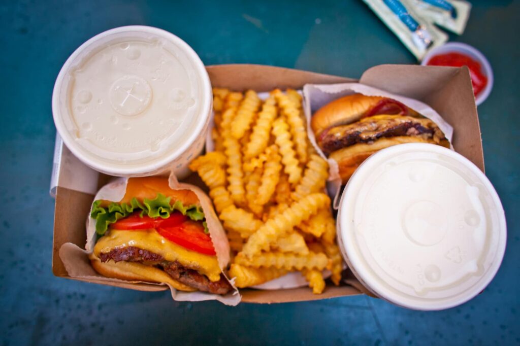 A tray with two hamburgers, French fries and two soft drinks