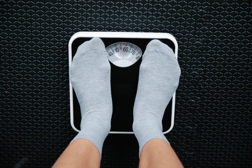 A person's feet standing on a small, black scale