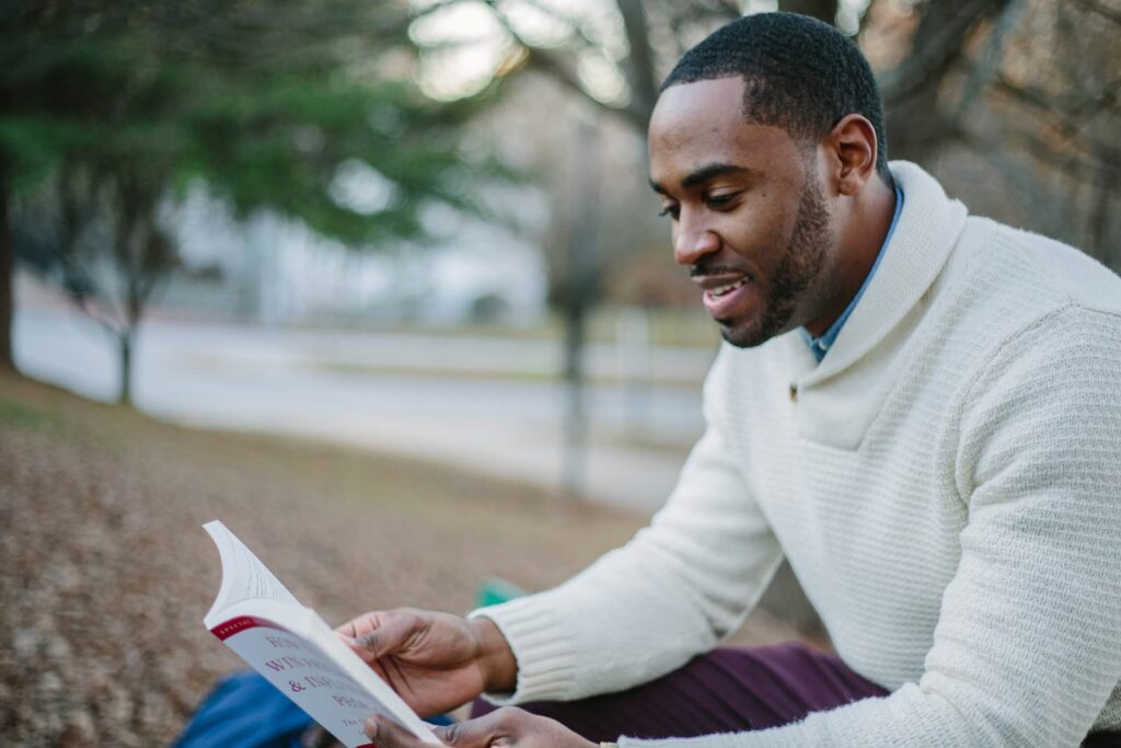 A man reading a book while sitting in a park