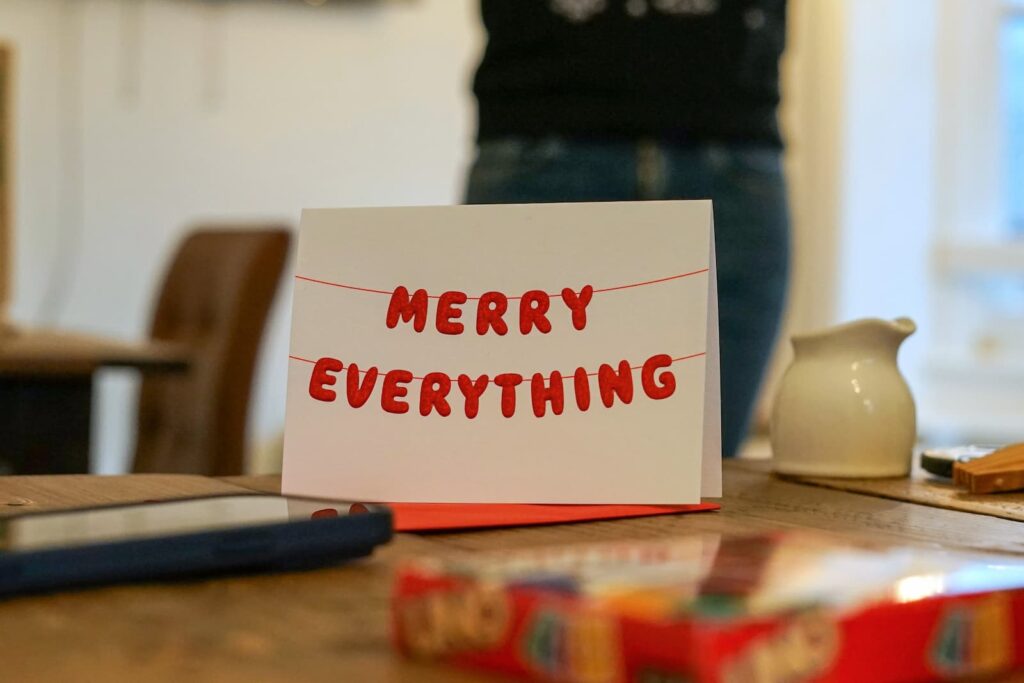 A holiday greeting card on a table next to a Christmas gift