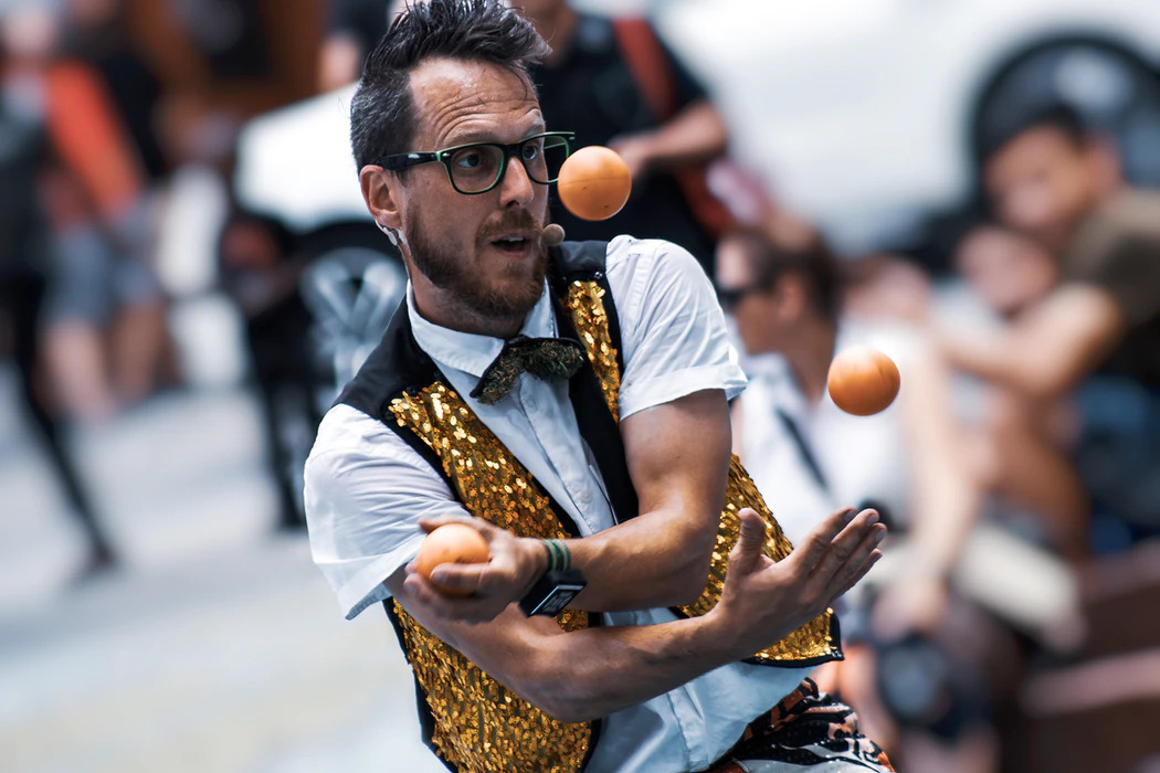 Un artista di strada che si destreggia con tre palline.