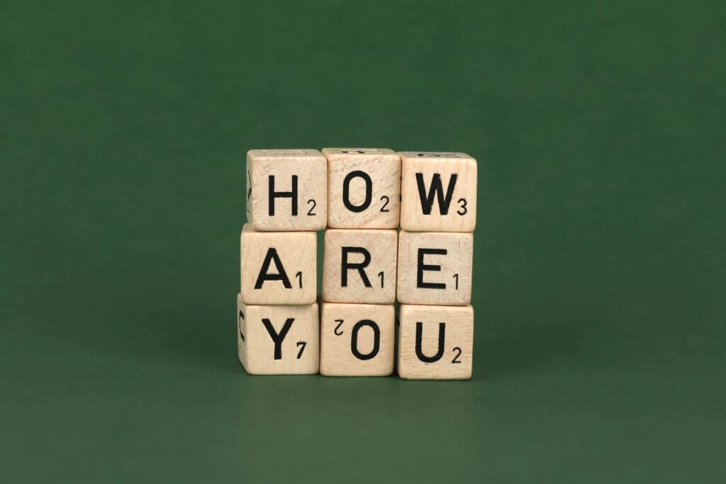 Small wood blocks with letters on them stacked to spell out "How are you"