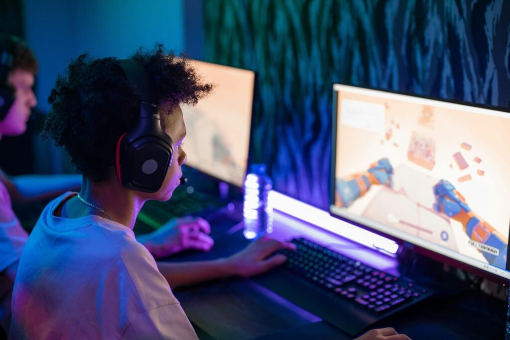 Boys wearing headphones and playing a video game on separate computers
