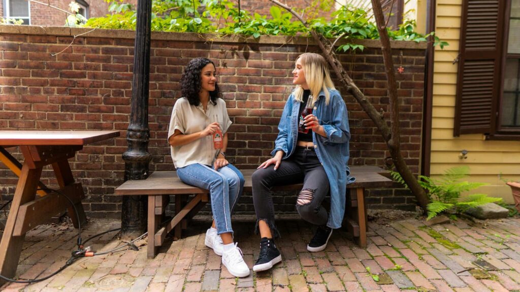 Two women making small talk while sitting outdoors
