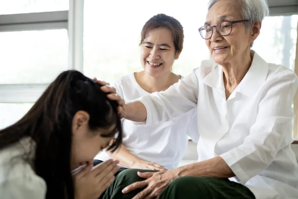 A young woman paying respect to her smiling grandmother