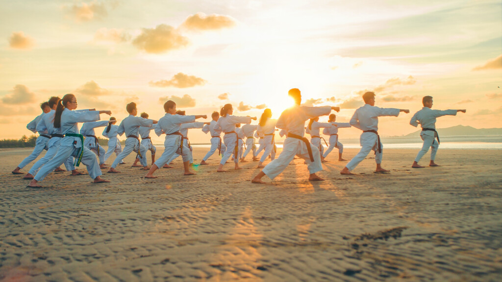 A group of people doing karate on a beach