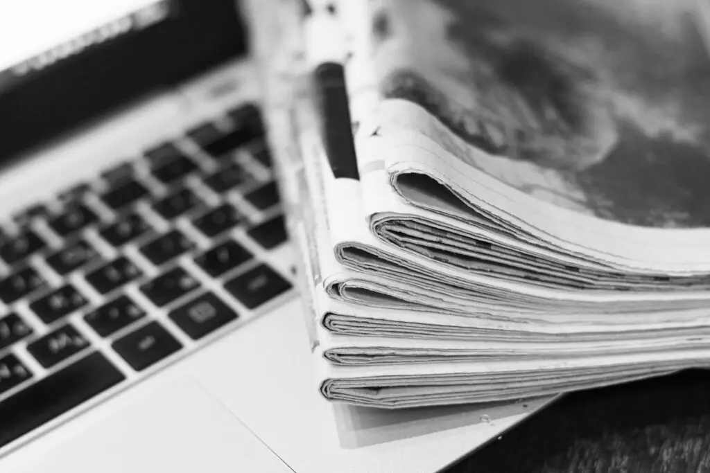 A stack of newspapers on top of a laptop computer