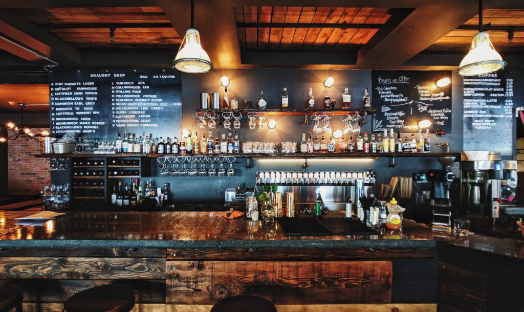 A bar with glasses and many bottles of different types of alcohol