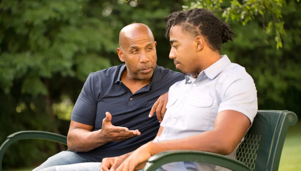 A man giving life advice to his nephew while sitting in a park