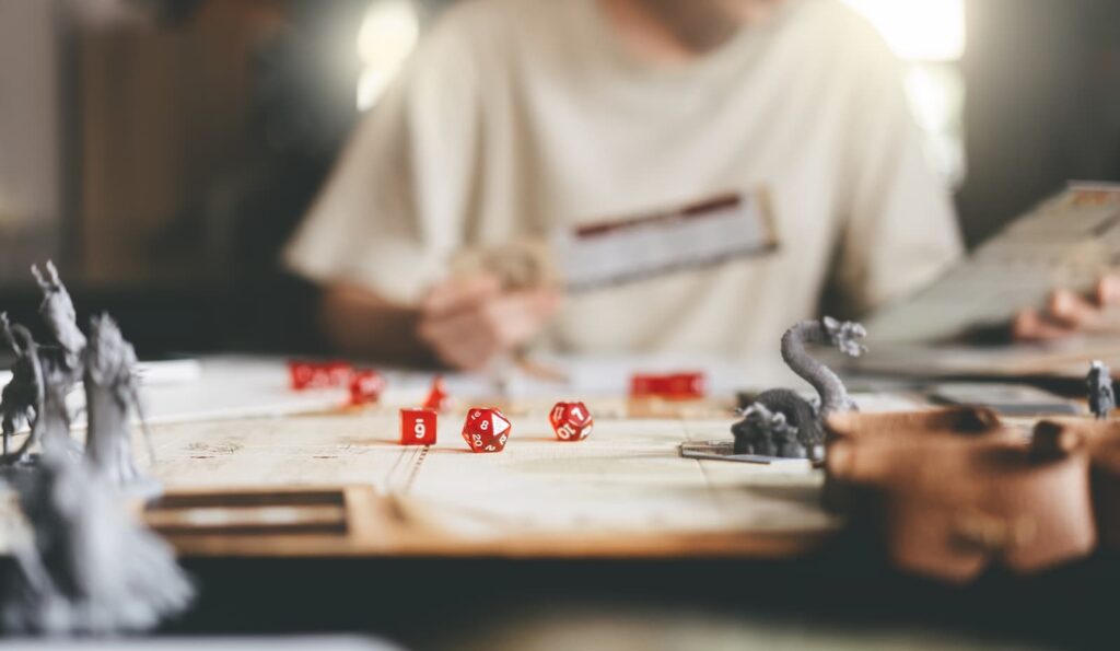 A player sitting in front of a game of Dungeons and Dragons, with die and game pieces