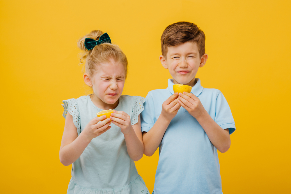 A girl and boy reacting to eating a very sour lemon