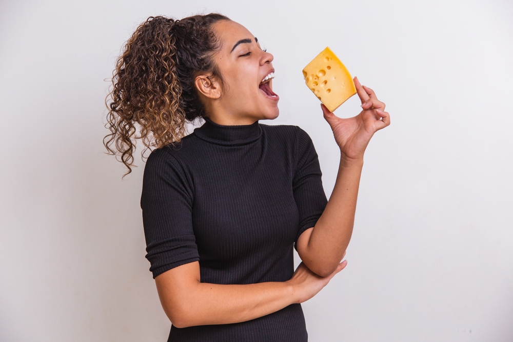 A young woman about to take a bite into a large piece of cheese