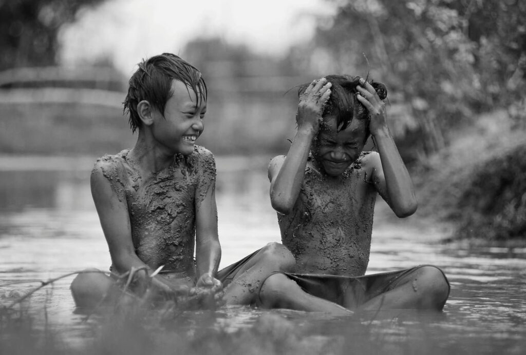 Two young boys playing in the mud