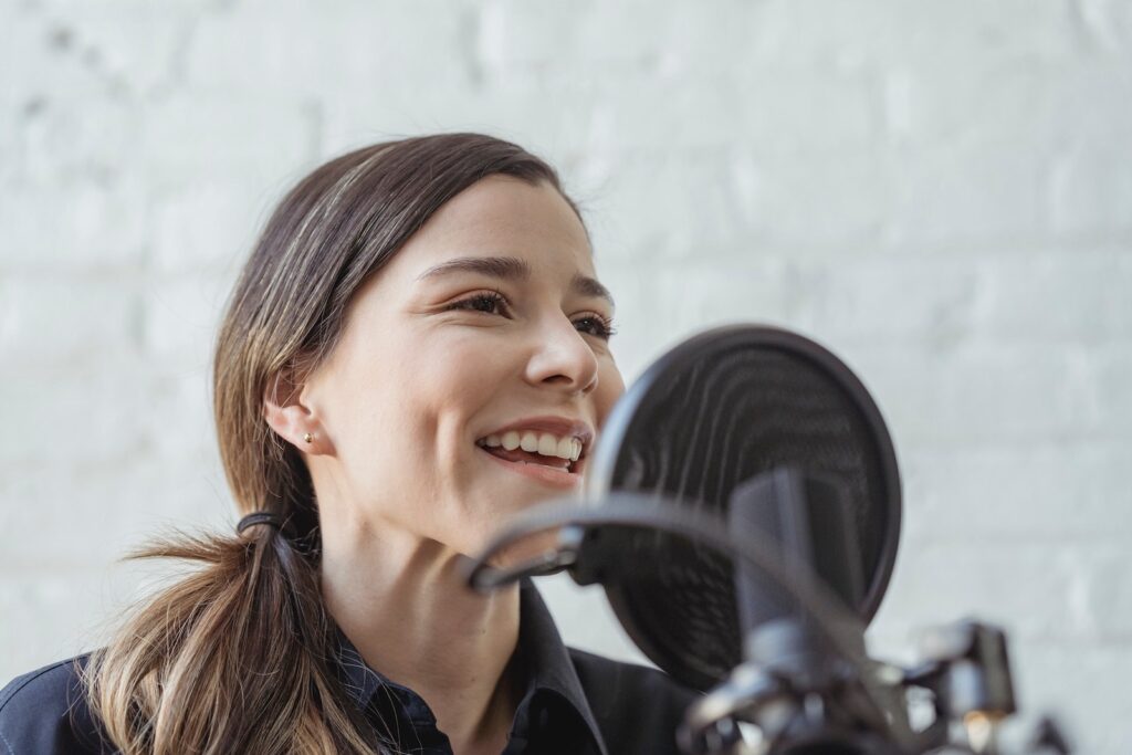 A woman speaking into a microphone and signing off at the end of her podcast