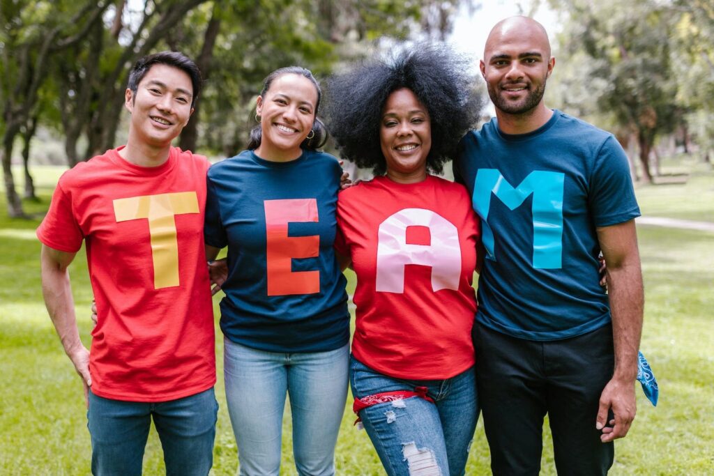 A group of international friends wearing shirts that spell out "TEAM" while standing in a park