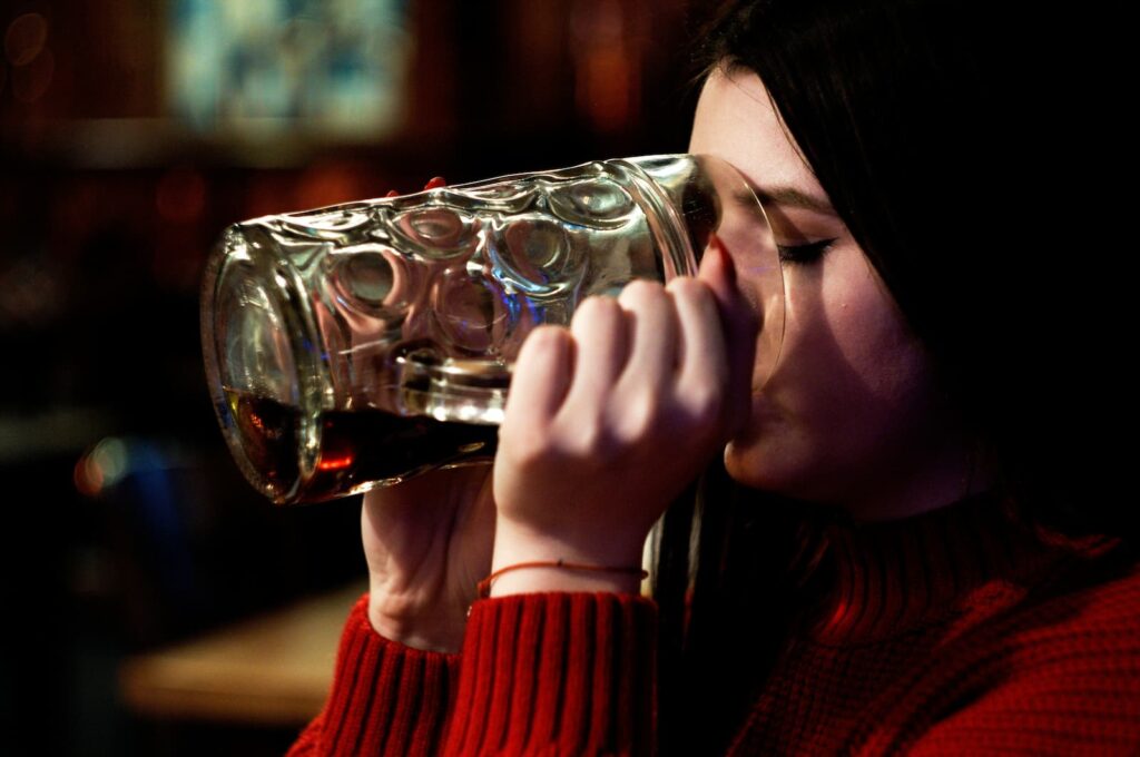 A woman chugging a large glass of beer
