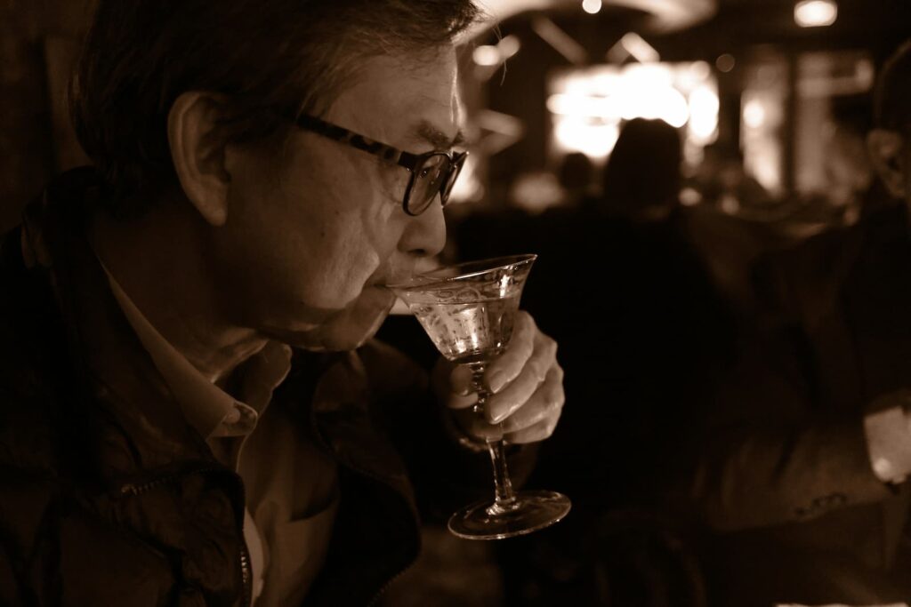 An older man sipping alcohol from a cocktail glass