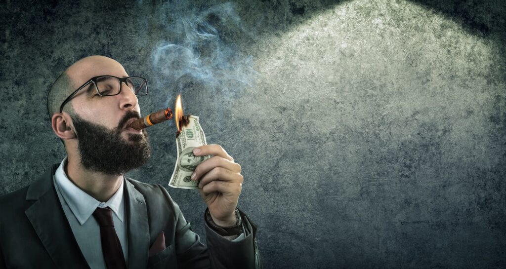 An arrogant businessman burning a one-hundred dollar bill with his cigar