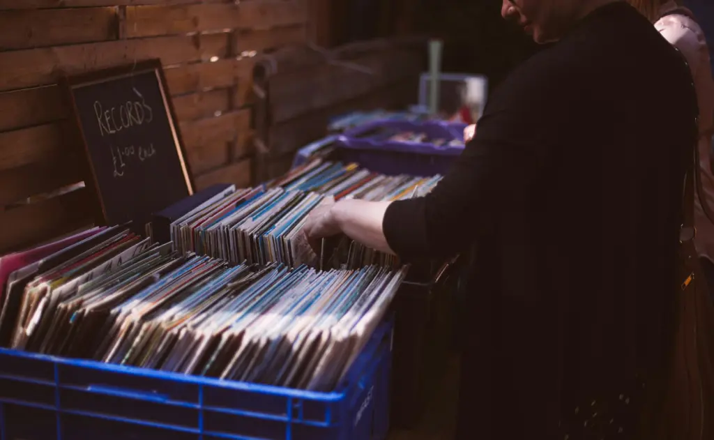 A woman looking through plastic bins full of used vinyl records