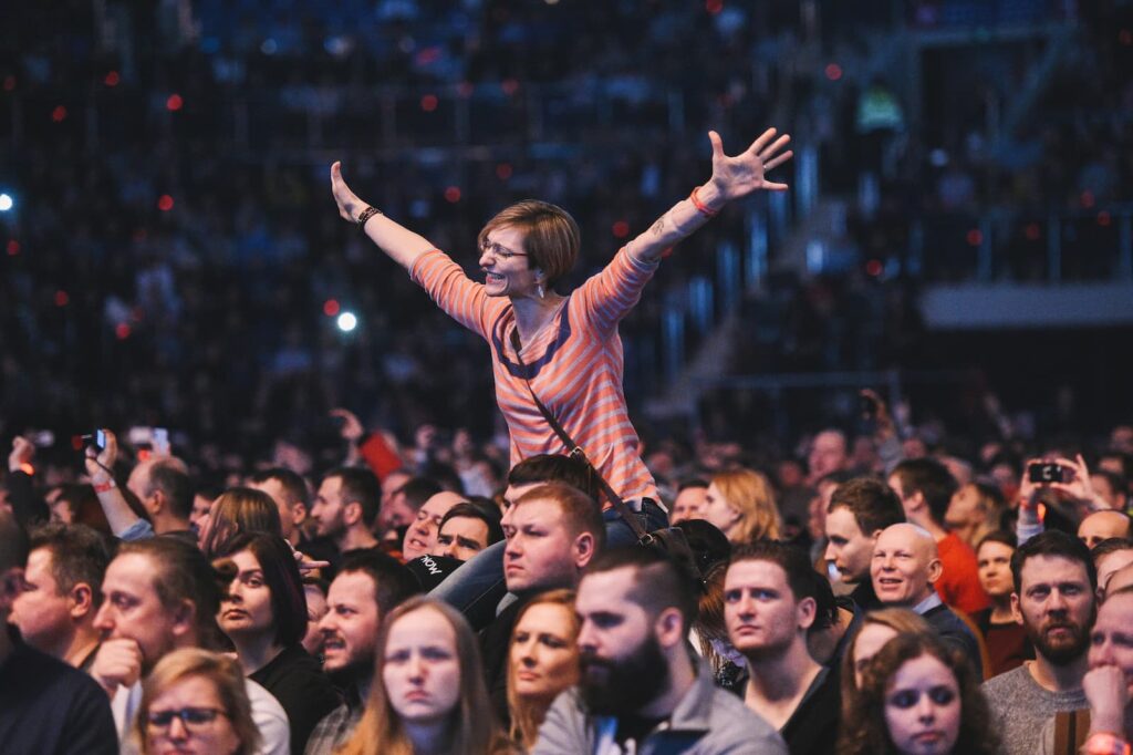 An smiling woman holding out her arms at a live concert