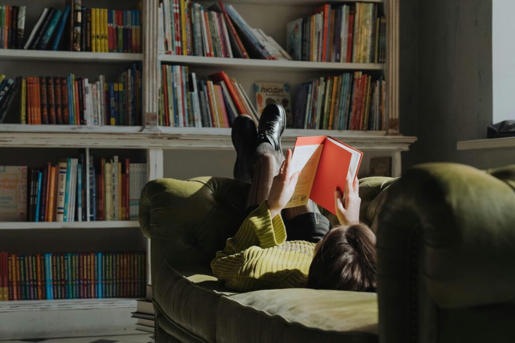 A woman reading while lying on a sofa