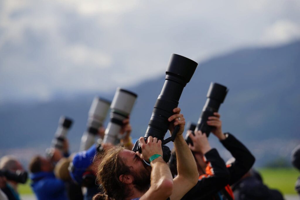 A group of people holding large cameras pointed at the sky
