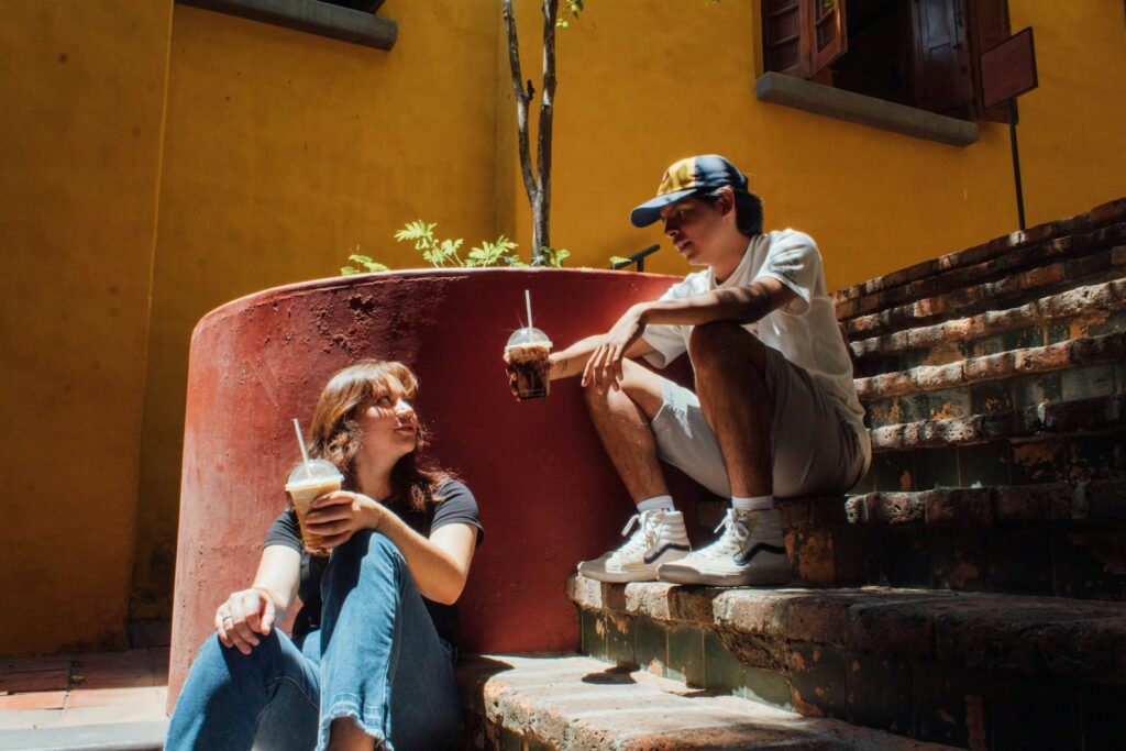 Two people chatting while sitting on a staircase and cold drinks