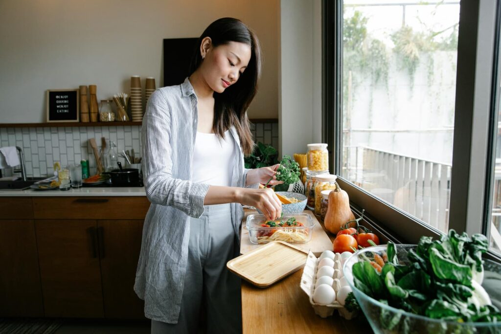 A young woman preparing a pasta in her kitchen