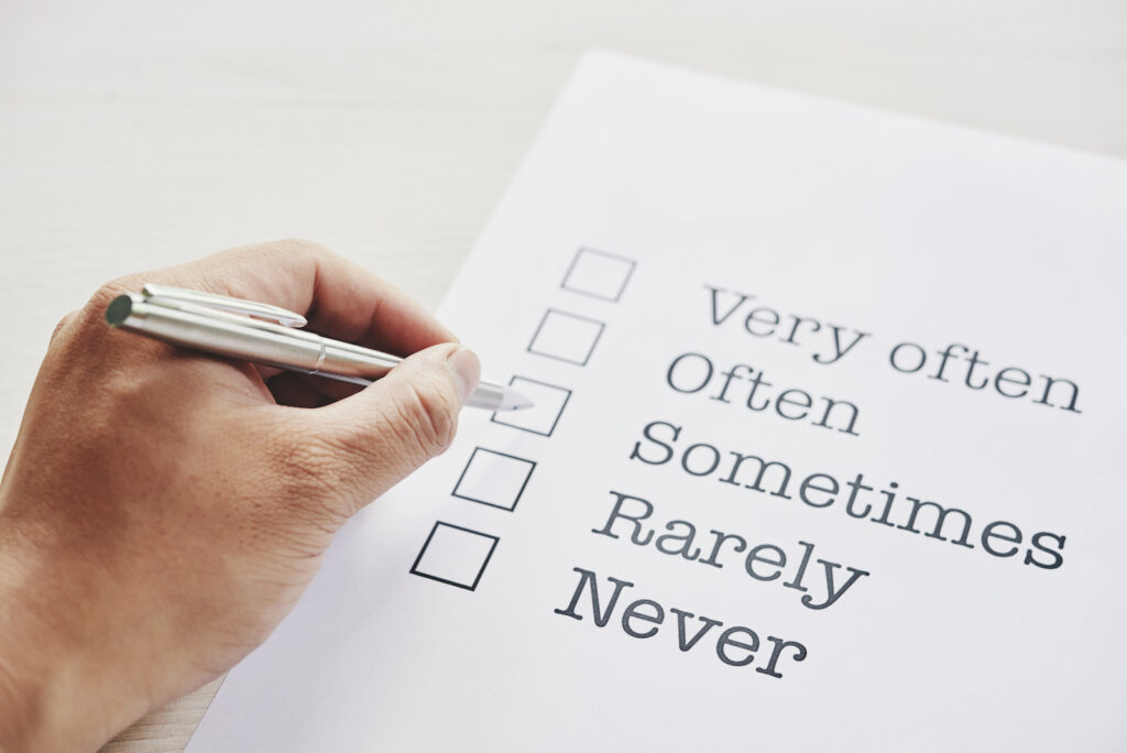 A person's hand checking boxes next to adverbs of frequency
