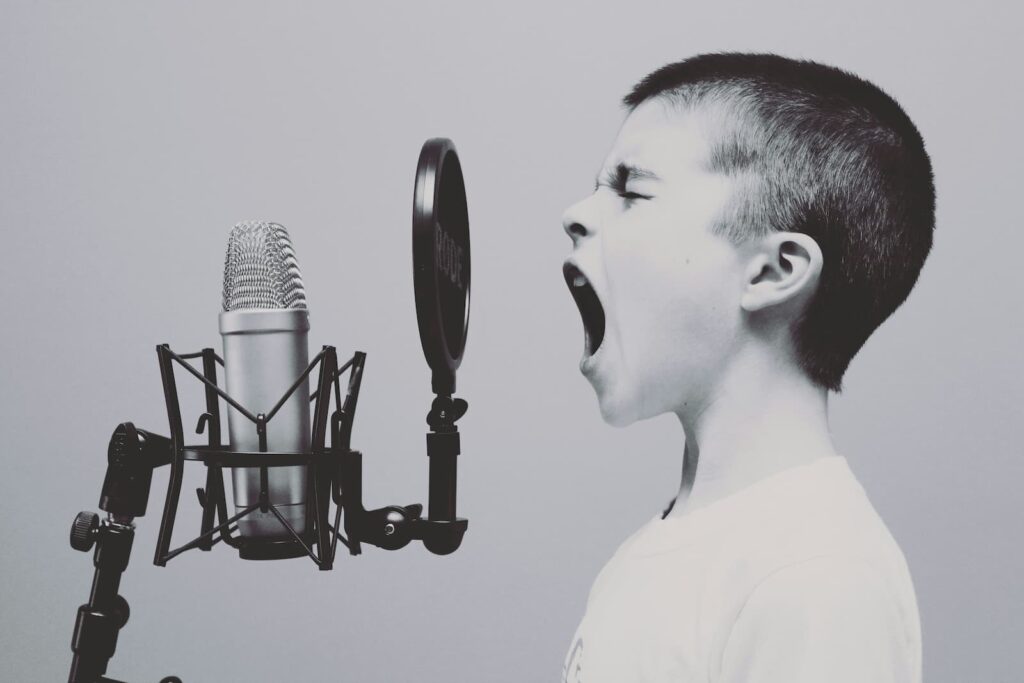 A little boy singing into a microphone protected with a pop shield
