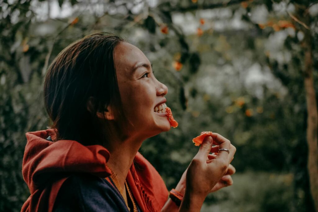 A woman smiling while eating fruit