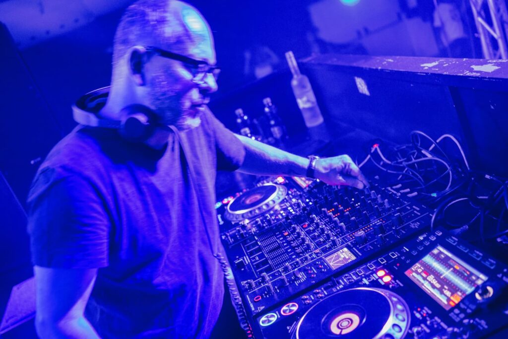 A DJ in a club adjusting the settings on a large mixer