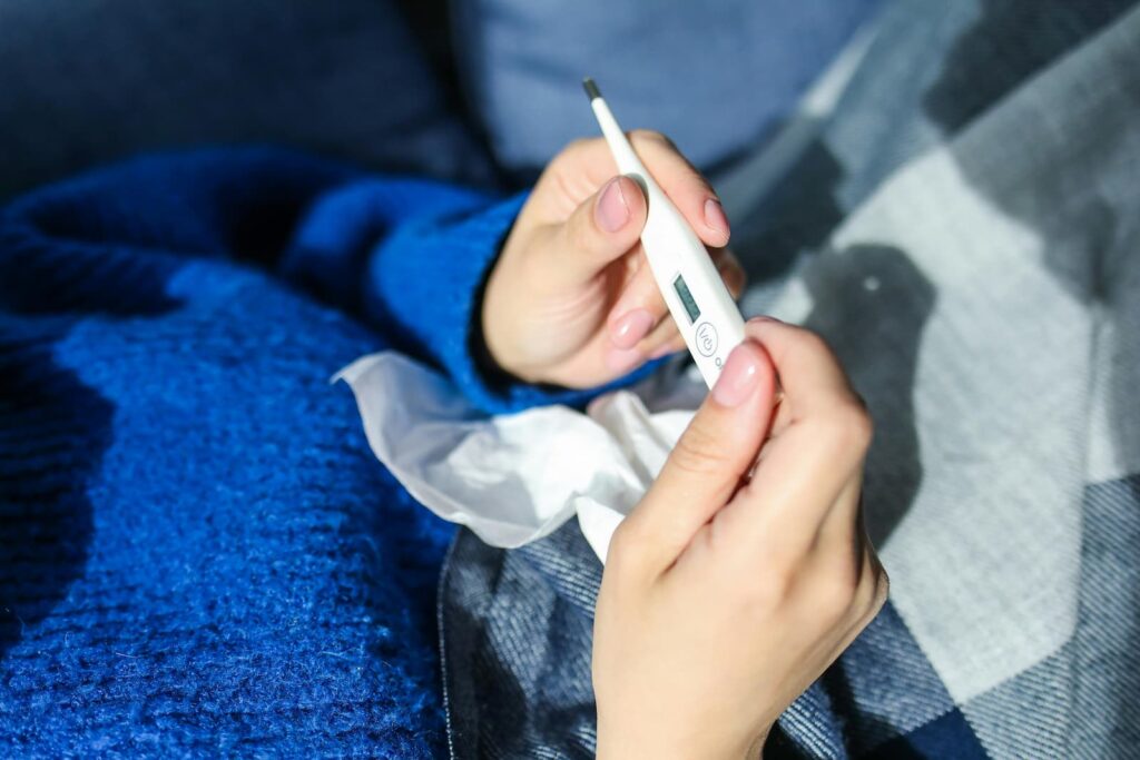 A sick woman holding a thermometer