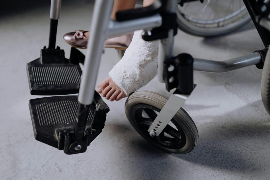 A girl sitting in a wheelchair with a cast on her leg