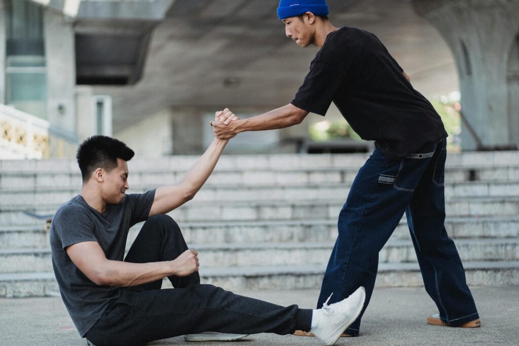 A man helping another to stand up