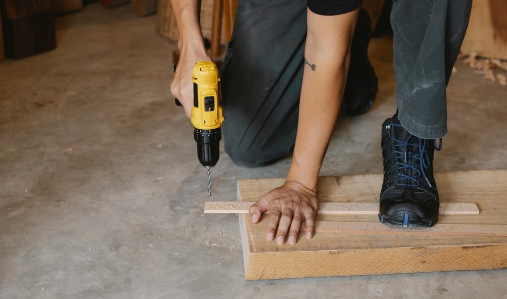 A man using a power tool to drill a hole in a piece of wood