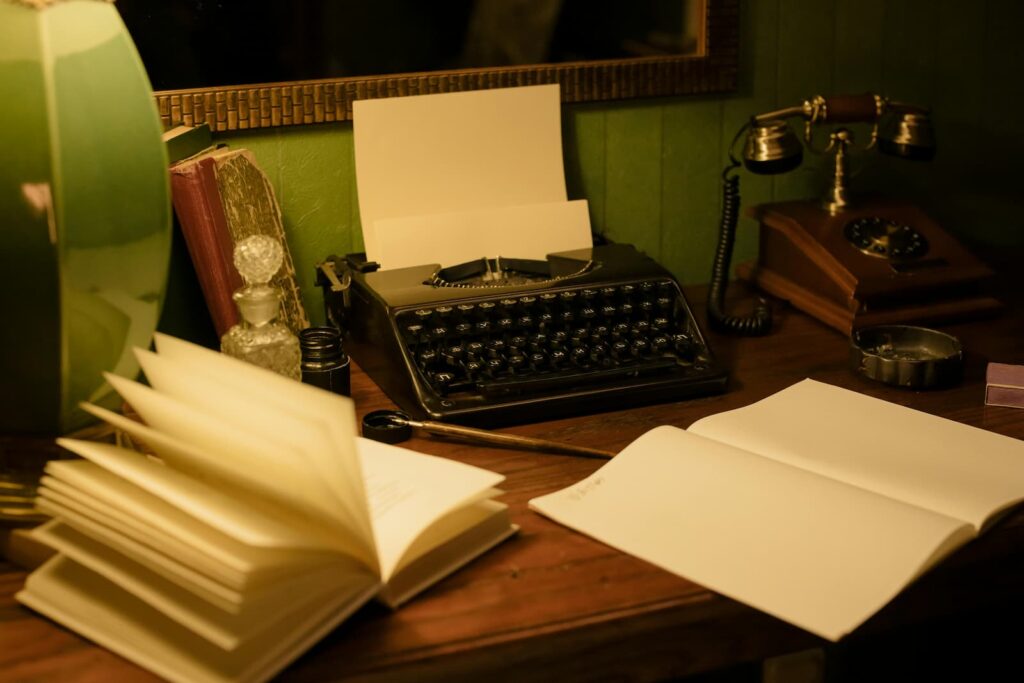 An old-fashioned typewriter on a desk covered in blank paper