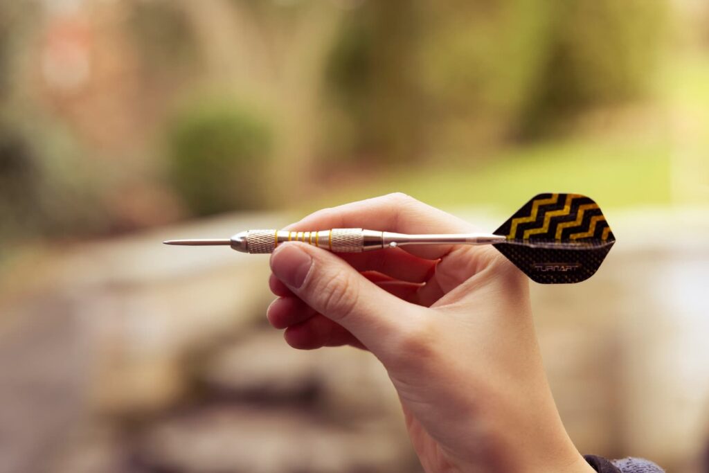 A person's hand holding a dart